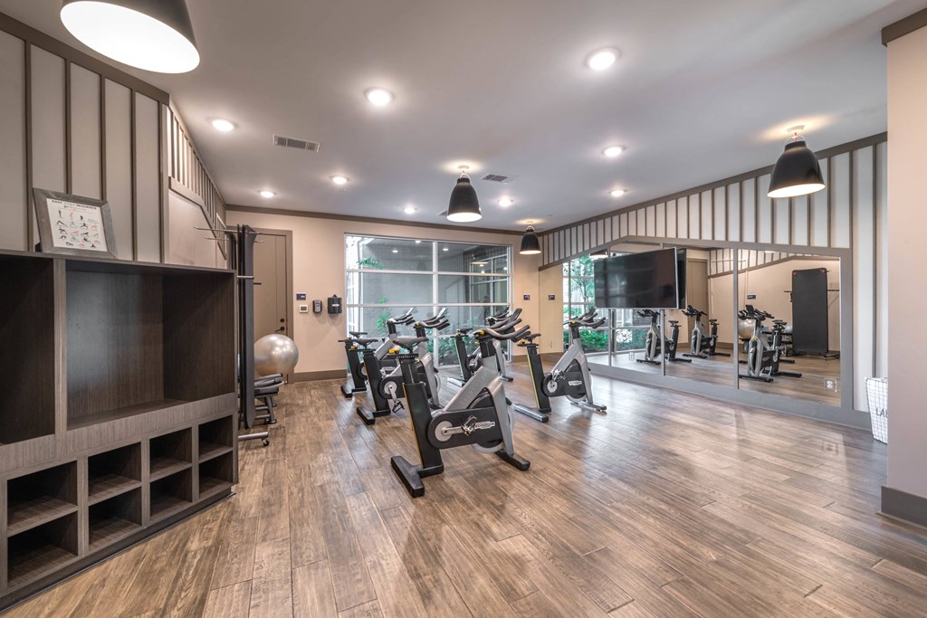 a gym with cardio machines and a tv