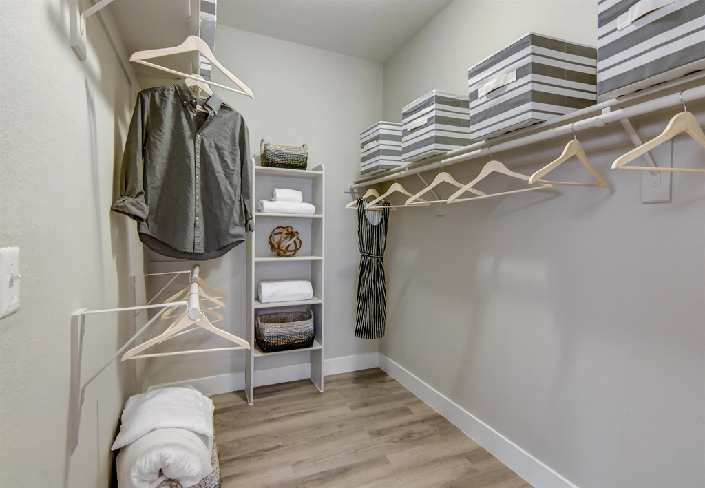 a walk in closet with a white closet organizer