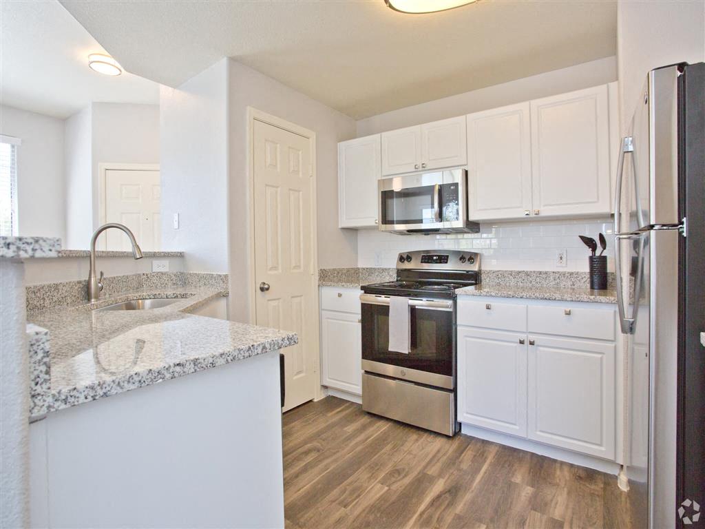 A kitchen with white cabinets and a granite countertop.