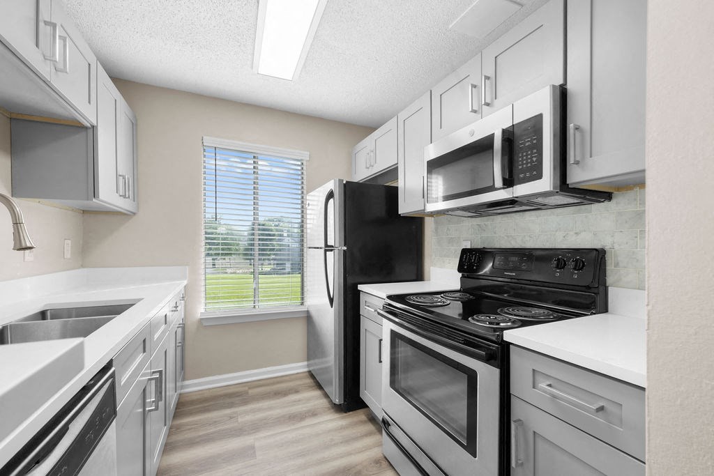 a kitchen with white cabinets and appliances and a window
