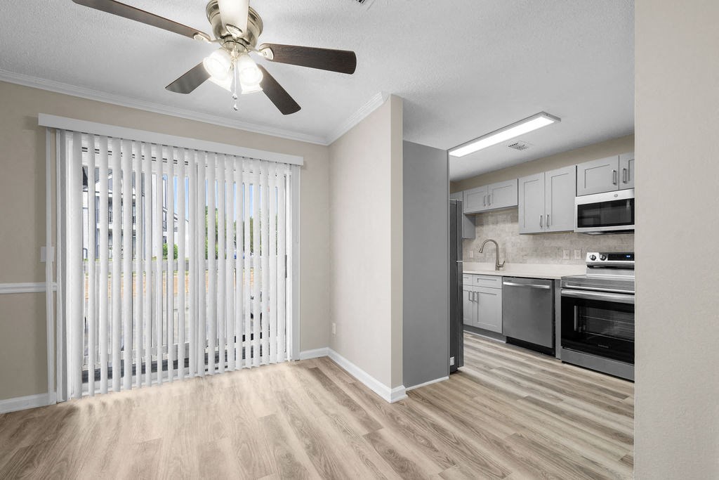 an empty living room with a ceiling fan and a kitchen