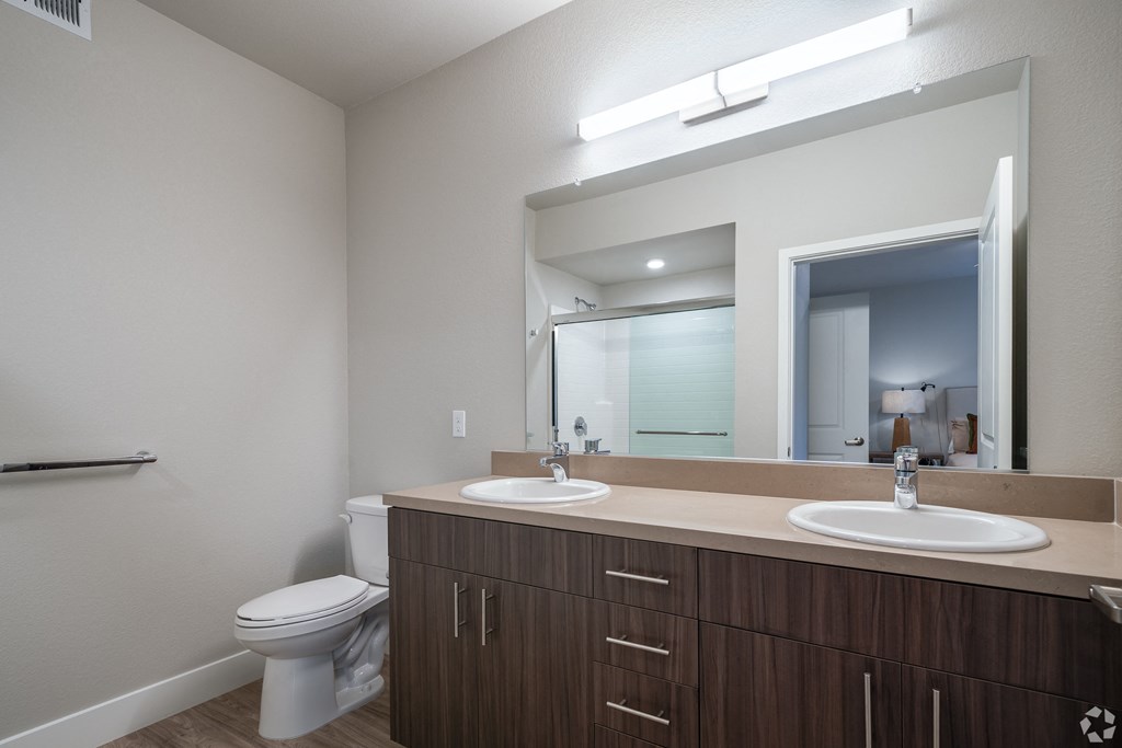 a bathroom with two sinks and a toilet and a large mirror