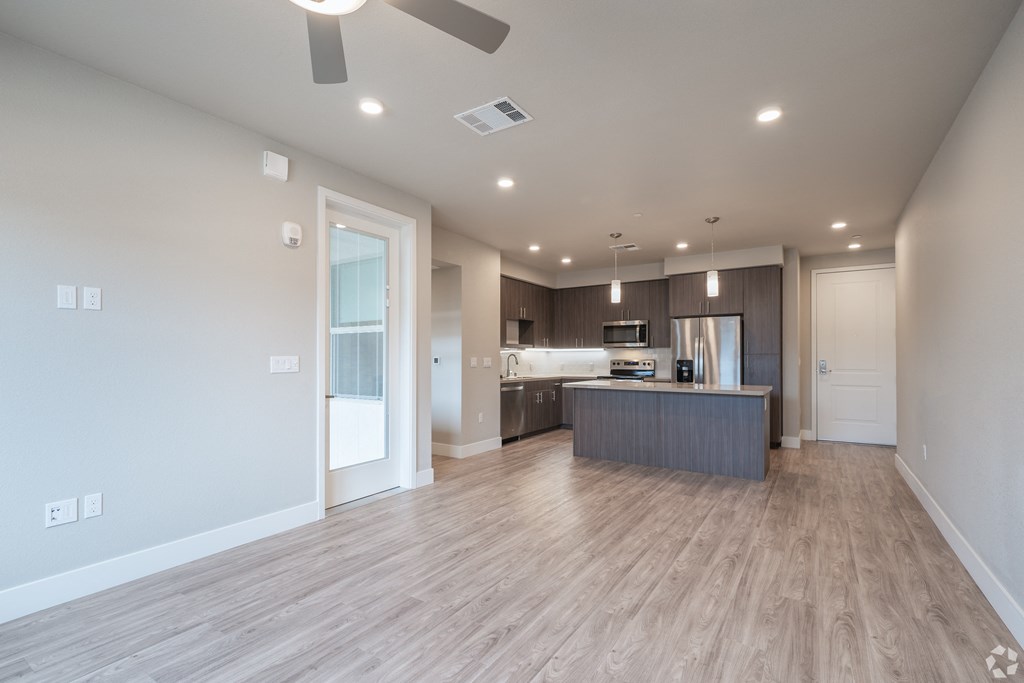a spacious living room with a kitchen and a ceiling fan