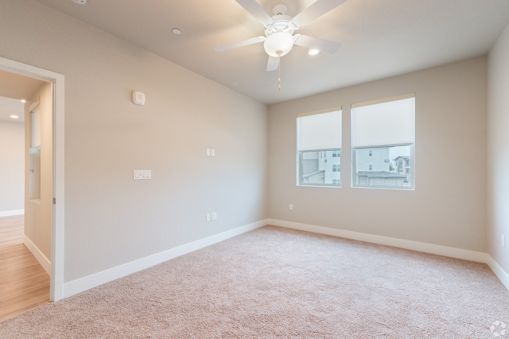 an empty living room with a ceiling fan and a window