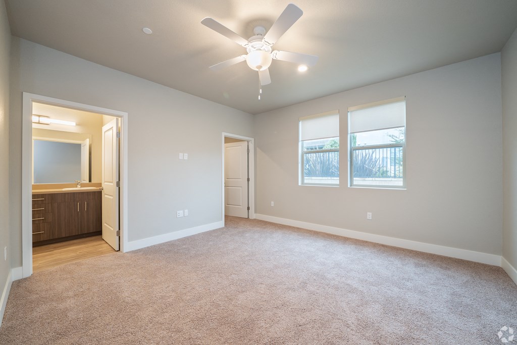 an empty living room with a ceiling fan and window