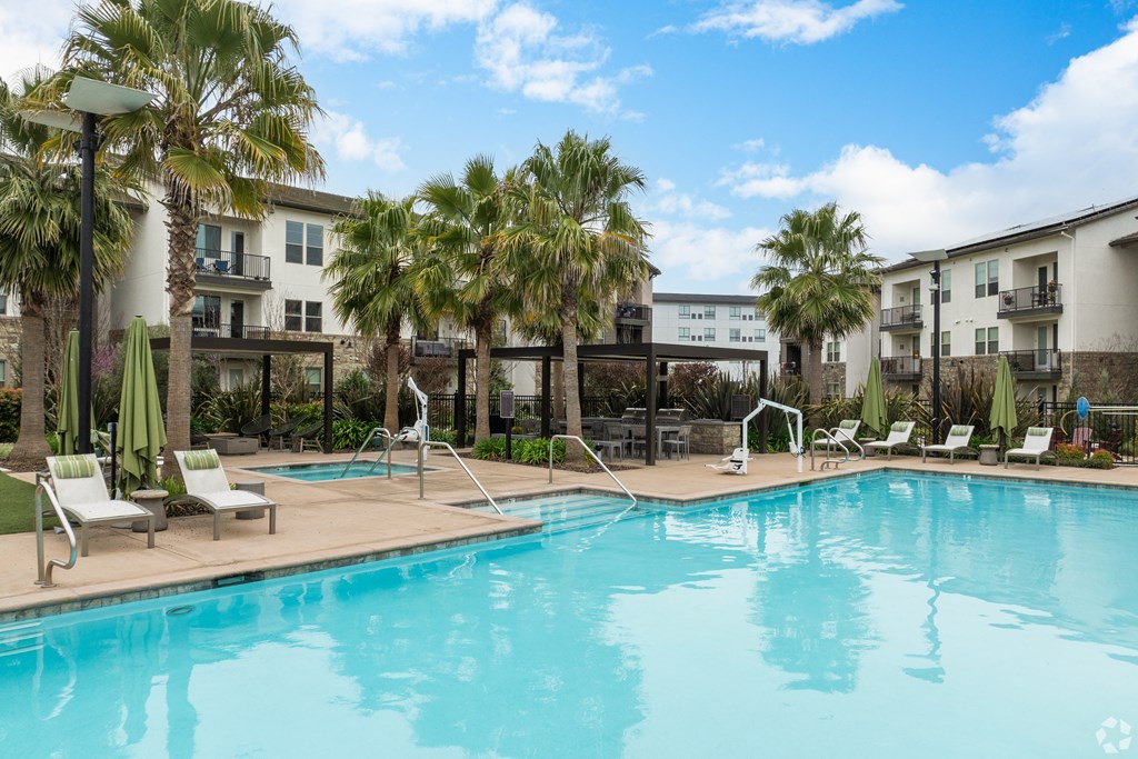 a swimming pool with palm trees and buildings in the background