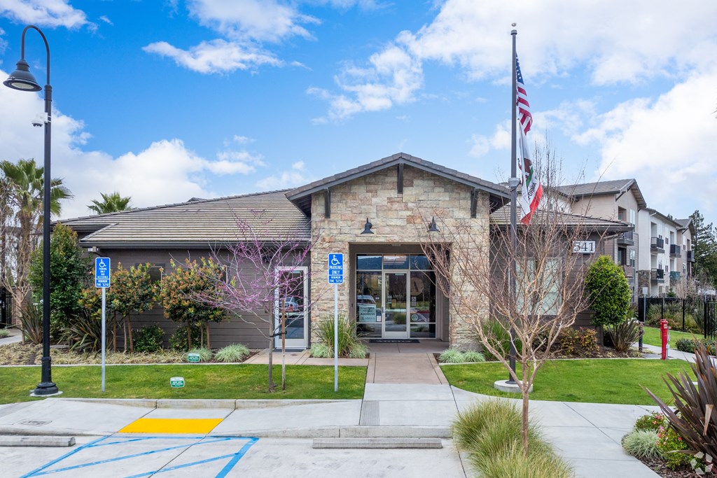 the front of a brick building with an flag and a sidewalk in front