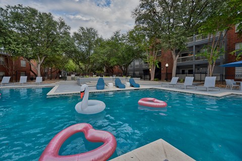 A pool with inflatable hearts and an inflatable swan at The Quarry Alamo Heights Apartments, Texas