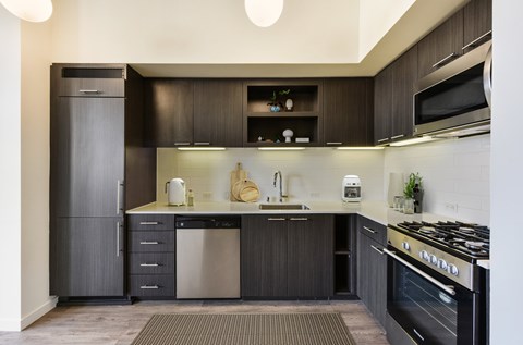 A modern kitchen with dark wood cabinets and stainless steel appliances.