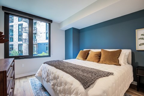 A bedroom with a large bed and a window overlooking a building.