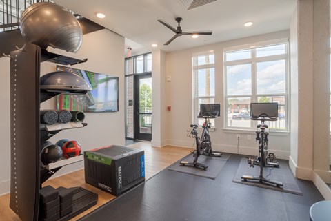 A gym with a row of exercise bikes and a rack of exercise balls.