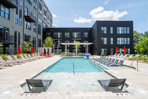 A large outdoor swimming pool surrounded by lounge chairs and umbrellas.