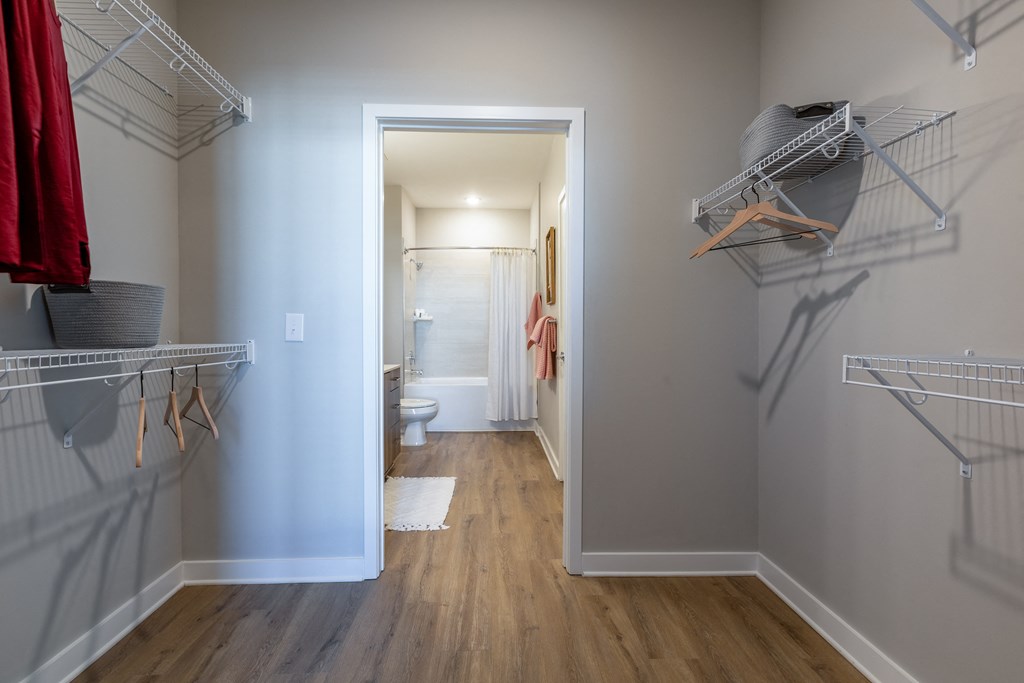 a walk in closet in a bedroom with a door leading to a bathroom