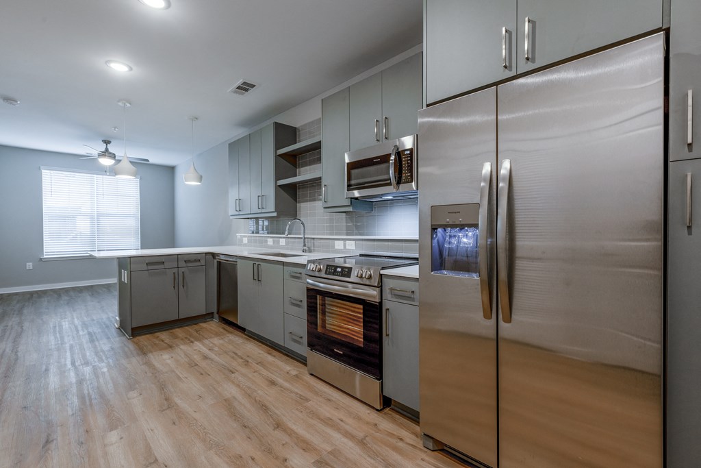 an empty kitchen with stainless steel appliances and a wooden floor