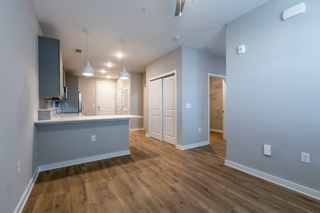 an empty living room and kitchen with wood floors and blue walls