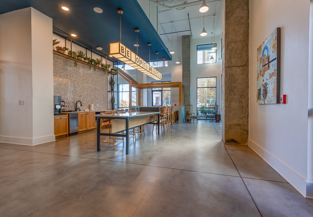 a dining room with a long table and chairs and a kitchen in the background