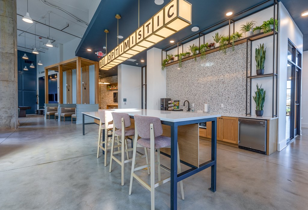 a long table with chairs in a room with a kitchen