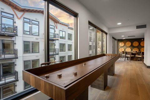 A shiny pool table is in the middle of a room with a balcony outside.