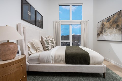 A bedroom with a large bed and a view of the city through the window.