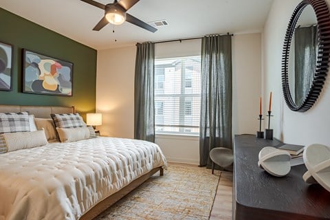A bedroom with a large bed and a ceiling fan.