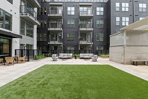 A large grassy area in front of a building with a white bench.