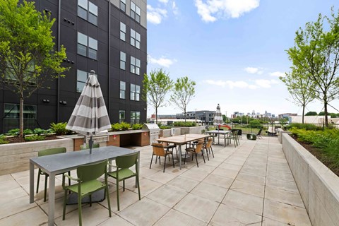 A patio with tables and chairs is surrounded by a black building.
