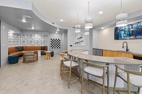 A modern kitchen with a curved island and bar stools.