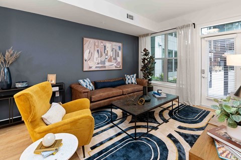 A living room with a yellow chair and a brown couch.