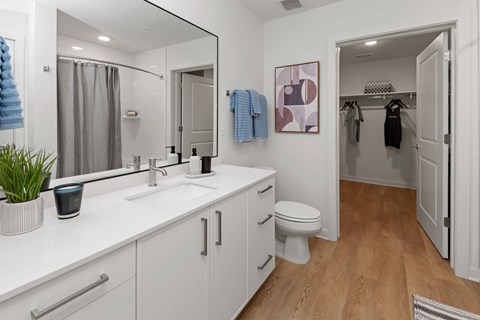 A bathroom with a white counter top and a white toilet.
