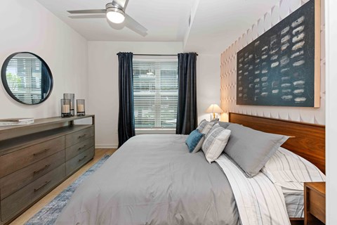 A bedroom with a large bed, a dresser, and a ceiling fan.