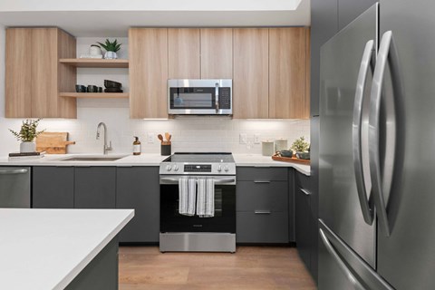 A modern kitchen with a stainless steel refrigerator and a microwave above the stove.