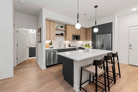 A modern kitchen with a white island and black countertops.
