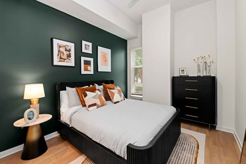 A bedroom with a bed, nightstand, and pictures on the wall.