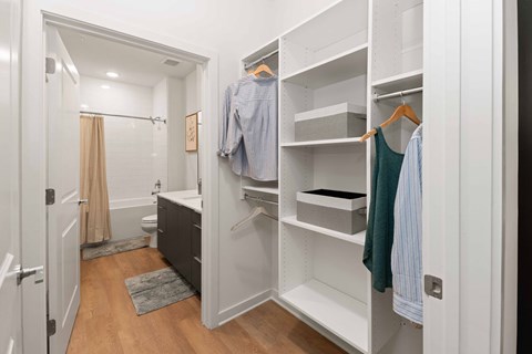 A white closet with clothes hanging and shelves.