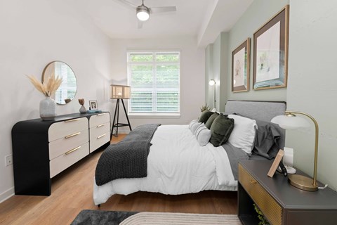 A bedroom with a bed, nightstand, and a mirror.