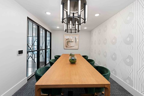 A conference room with a long table and green chairs.