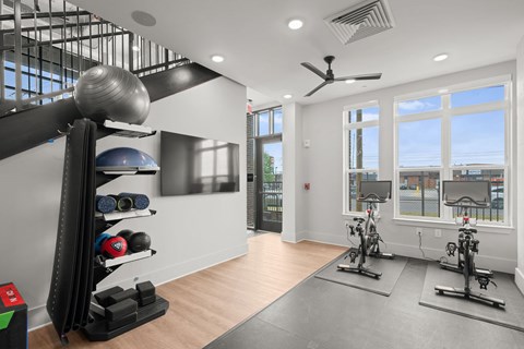 A gym with a row of stationary bikes and a rack of weights.