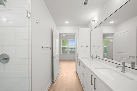 A white bathroom with a walk in shower and a vanity with a mirror.