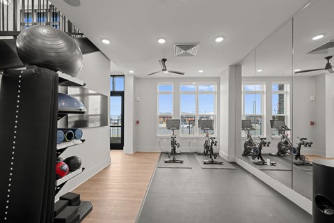 A gym with a variety of exercise equipment including treadmills, stationary bikes, and weights.