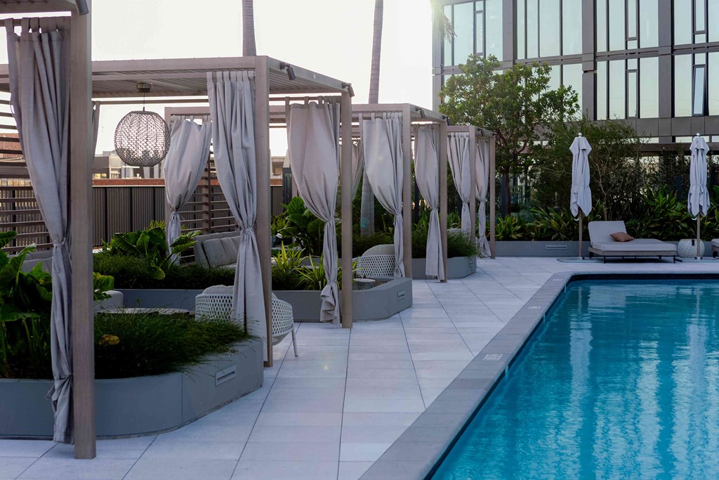 A pool area with a white umbrella and a white chair.