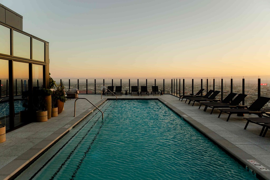 A swimming pool with lounge chairs and a view of the ocean.