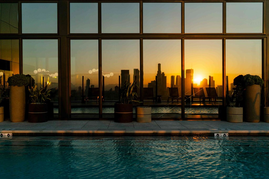A pool with a view of the city skyline at sunset.