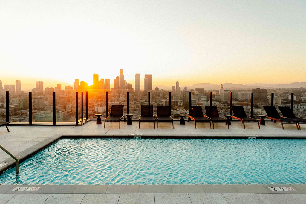 A pool with chairs and a city skyline in the background.
