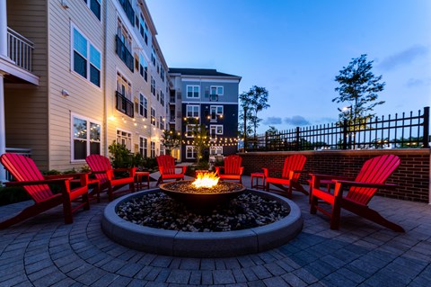 A fire pit surrounded by red chairs in a courtyard.