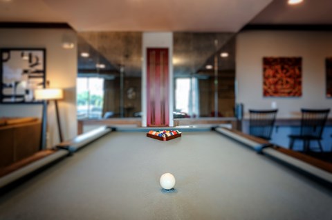 A pool table with a white ball in the middle of it.