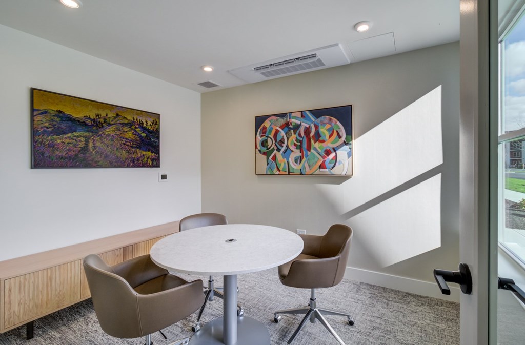 A room with a white table and chairs and two paintings on the wall.