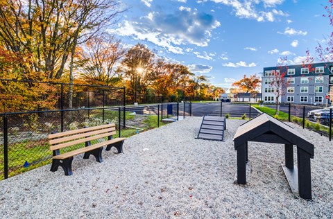 A park with a bench, a playground and trees.