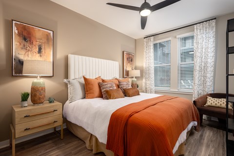 A bedroom with a bed, nightstand, and a painting on the wall.