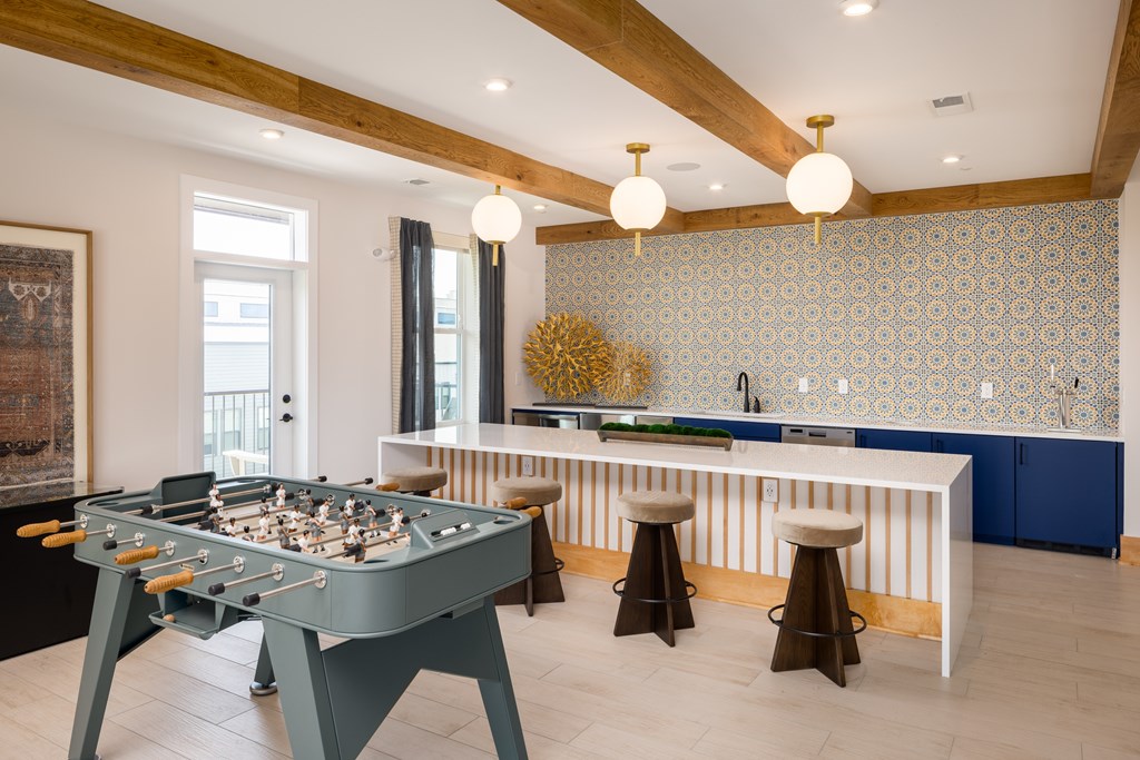 A foosball table is in the middle of a room with a blue and white tiled backsplash.