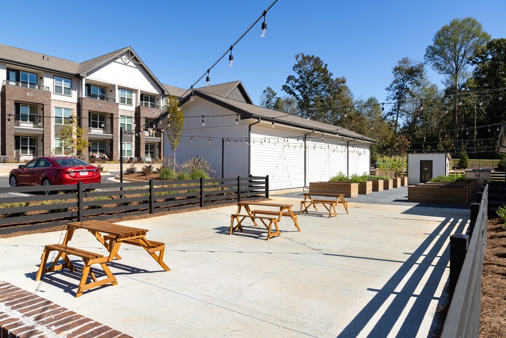 a patio with wooden benches and tables in front of a building
